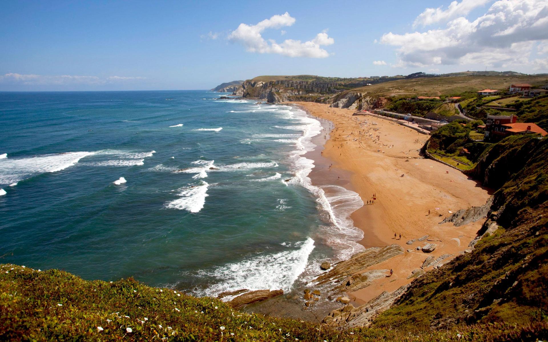 Golden sandy beach of Playa de Sopelana with waves and surfers